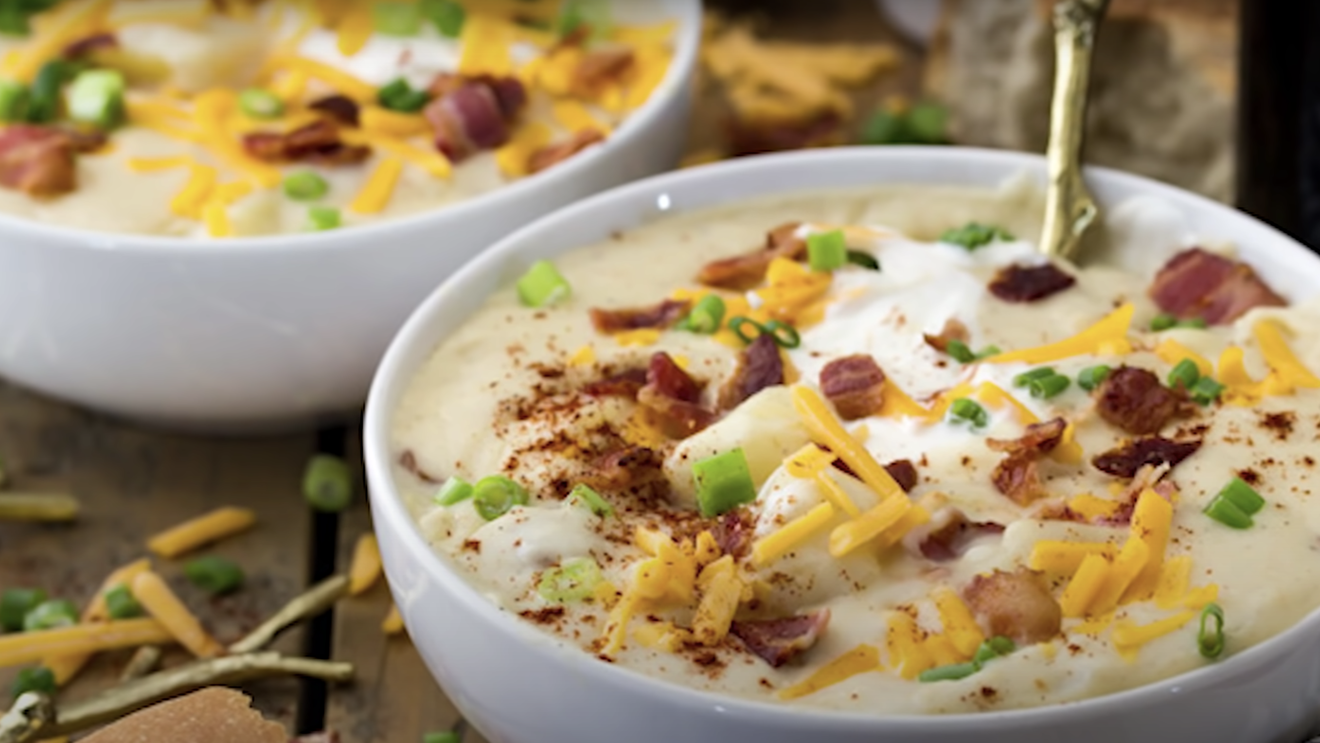 bowl of potato soup topped with cheese, chives, and bacon