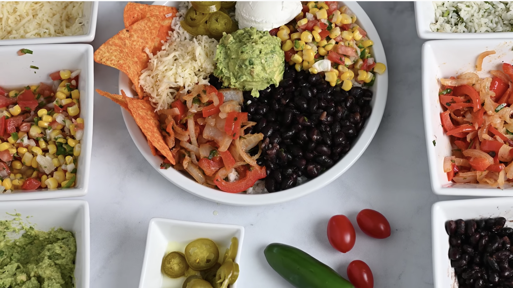 A veggie burrito bowl with ingredients around it