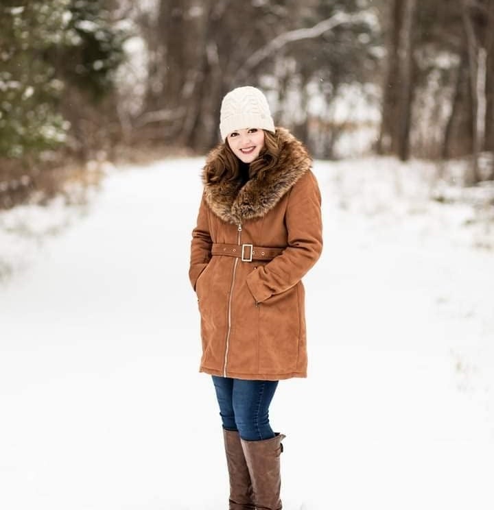 Reviewer in the snow wearing the tan suede jacket belted at waist with fur hood