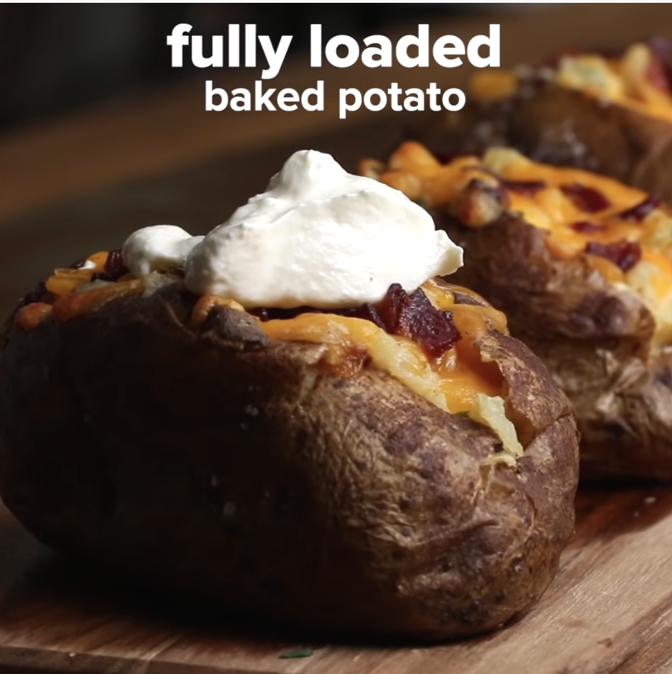 A fully loaded baked potato with cheese, bacon, and sour cream