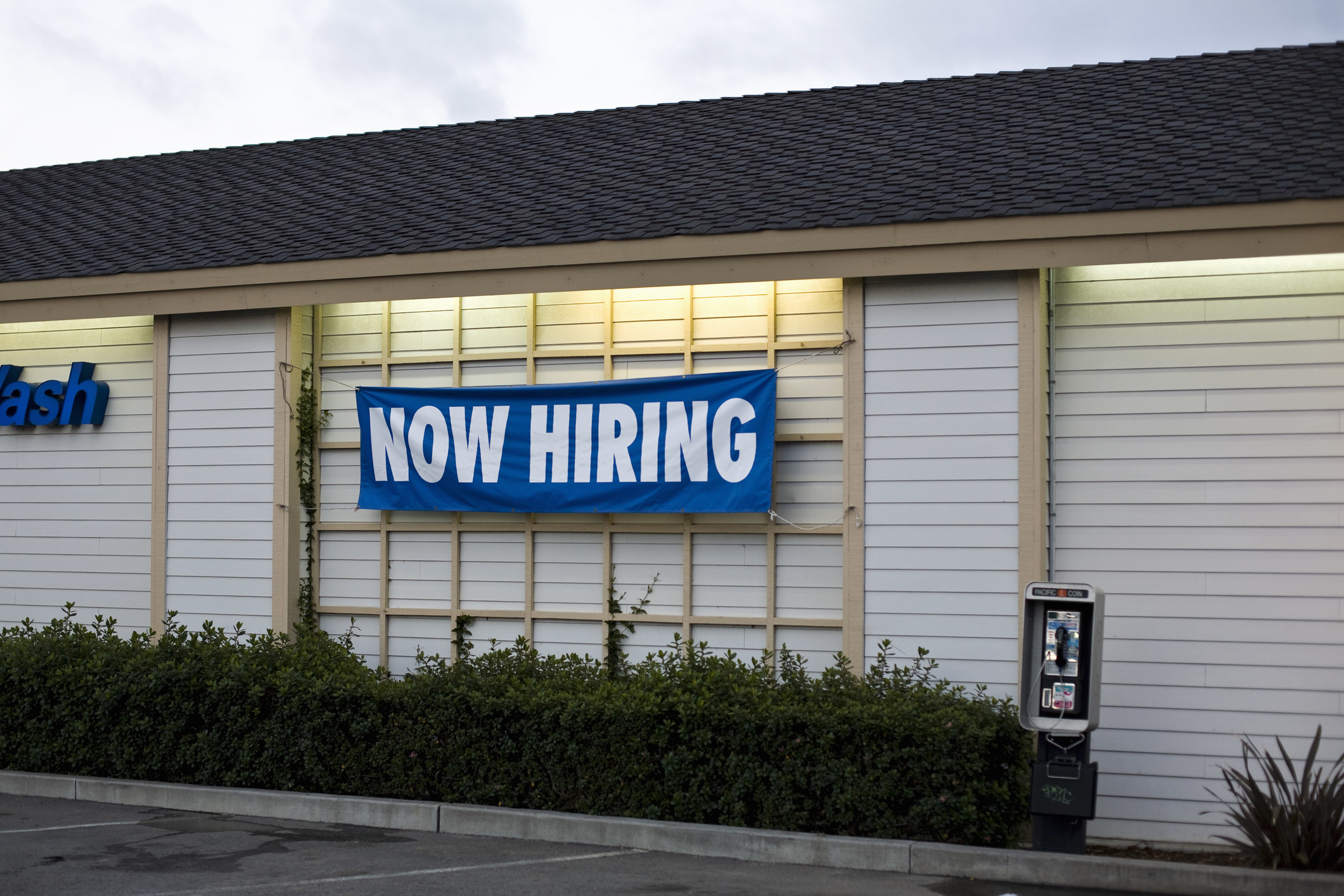 a restaurant exterior with a &quot;now hiring&quot; banner
