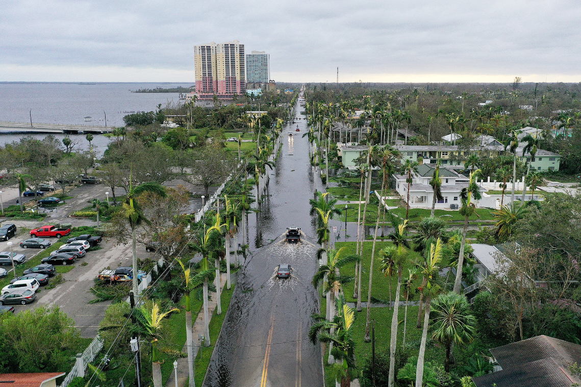 an aerial shot of florida&#x27;s urban coastline, cars drive through a flooded road