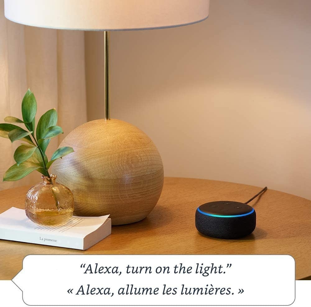 the echo dot on a table next to a lamp and vase