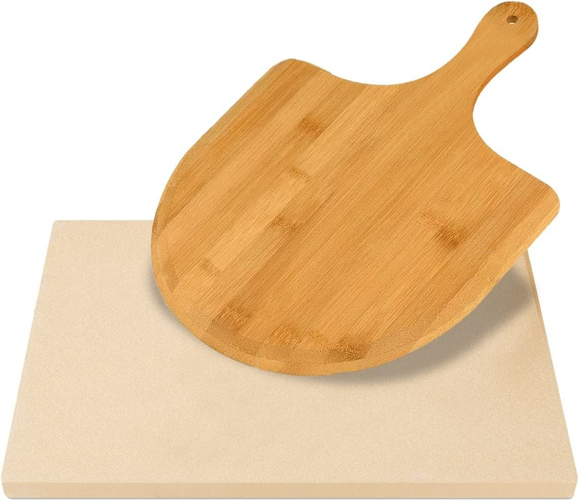 A square-shaped pizza stone with a wooden pizza peel