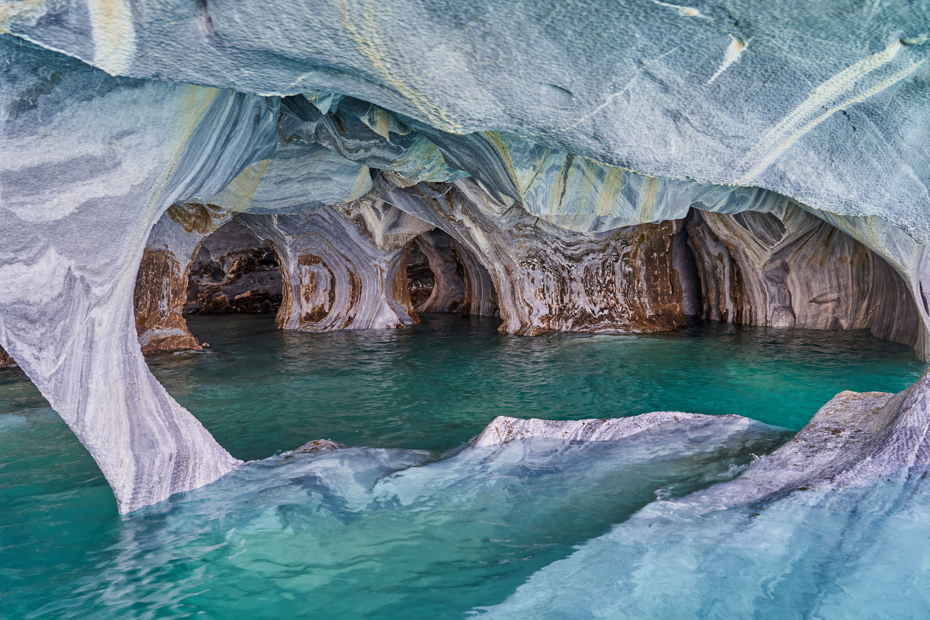 Blue-green water amid caves with blue-and-white swirl marble