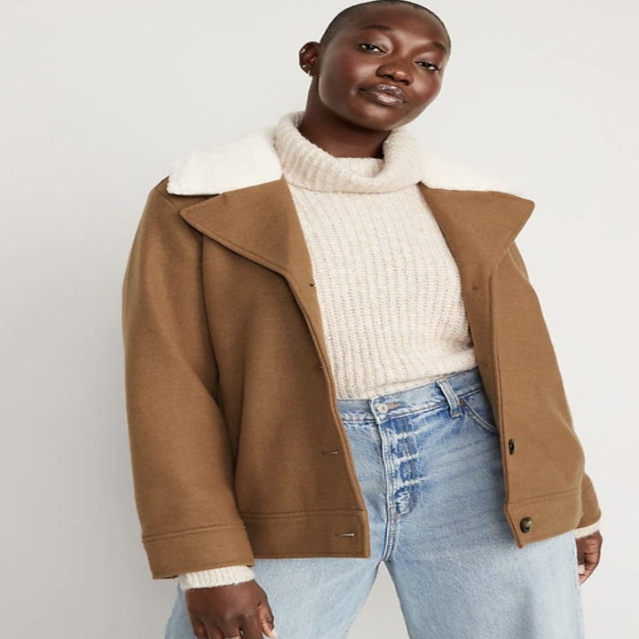 Model wearing the tan button-up jacket open over white sweater