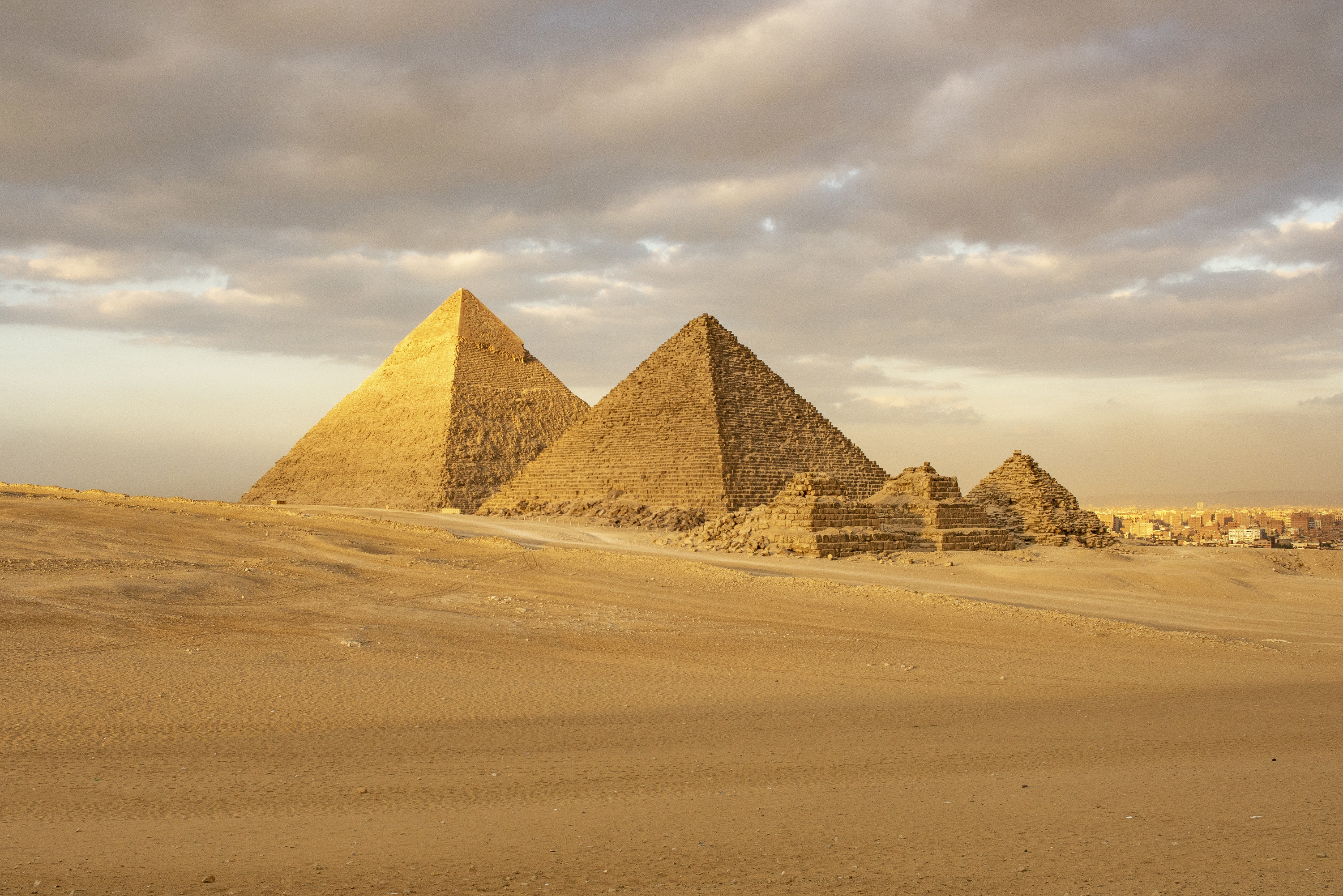 Two large pyramids and smaller ones amid sand