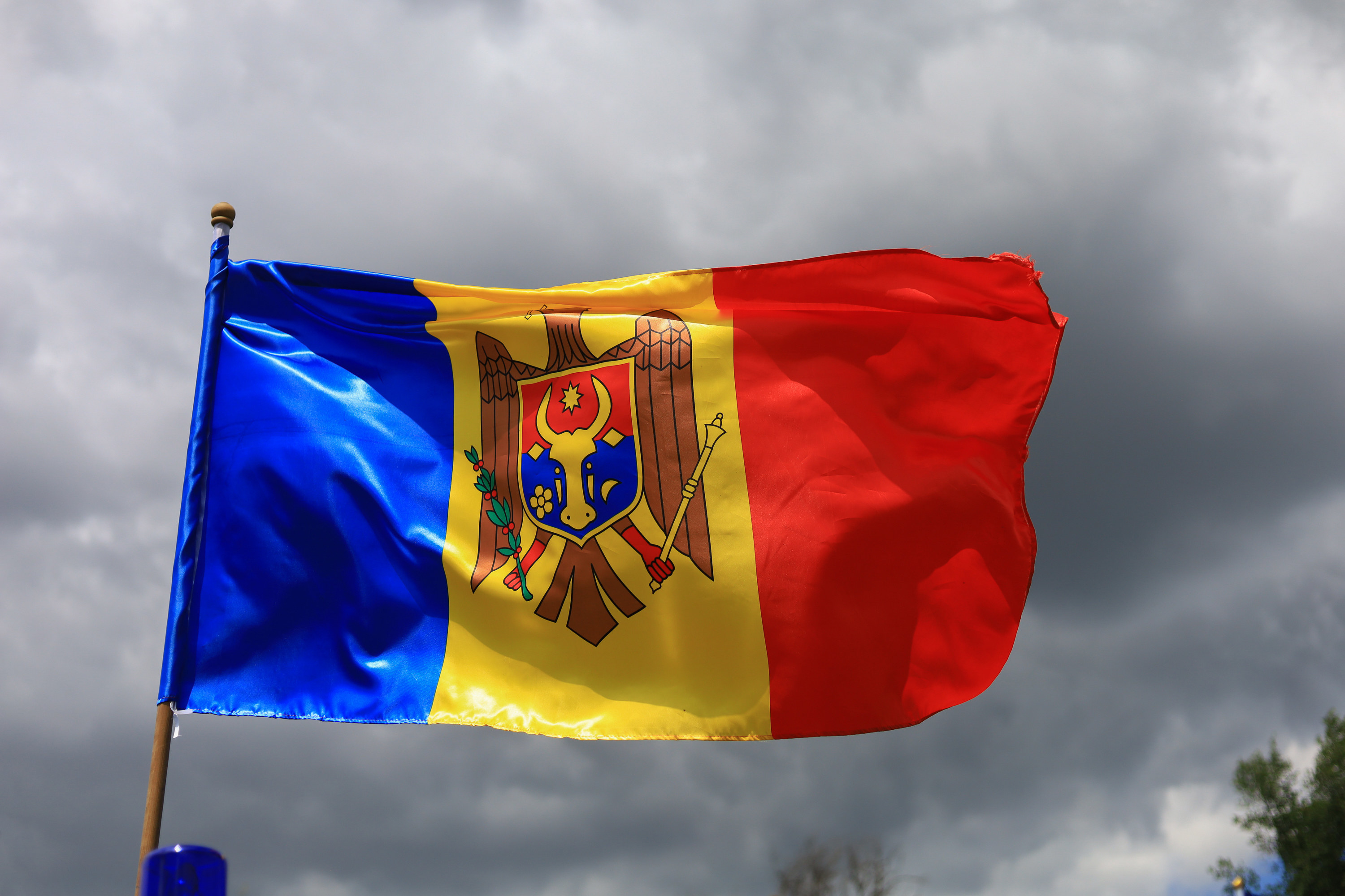 Flag of Moldova, a vertical triband of blue, yellow, and red,  with the coat of arms of Moldova (an eagle holding a shield)