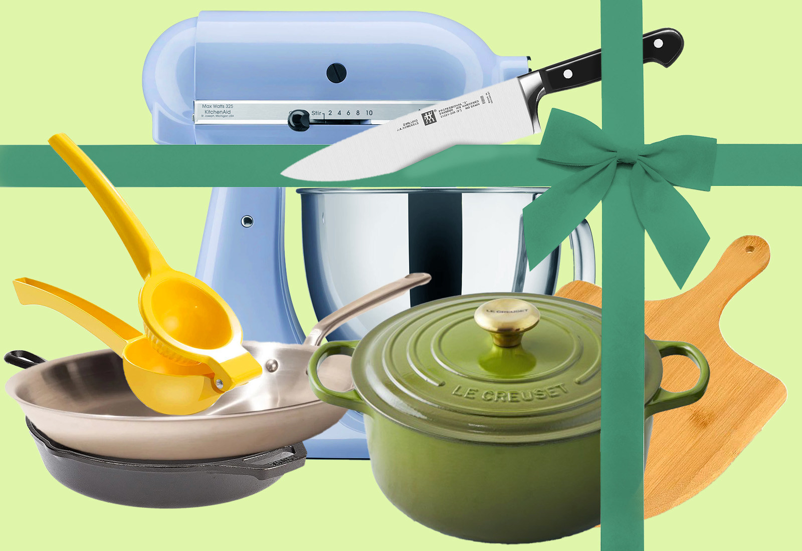 A stand mixer, two pans, a citrus juicer, a dutch oven, and a pizza peel behind a big green bow. A kitchen knife is cutting through the bow