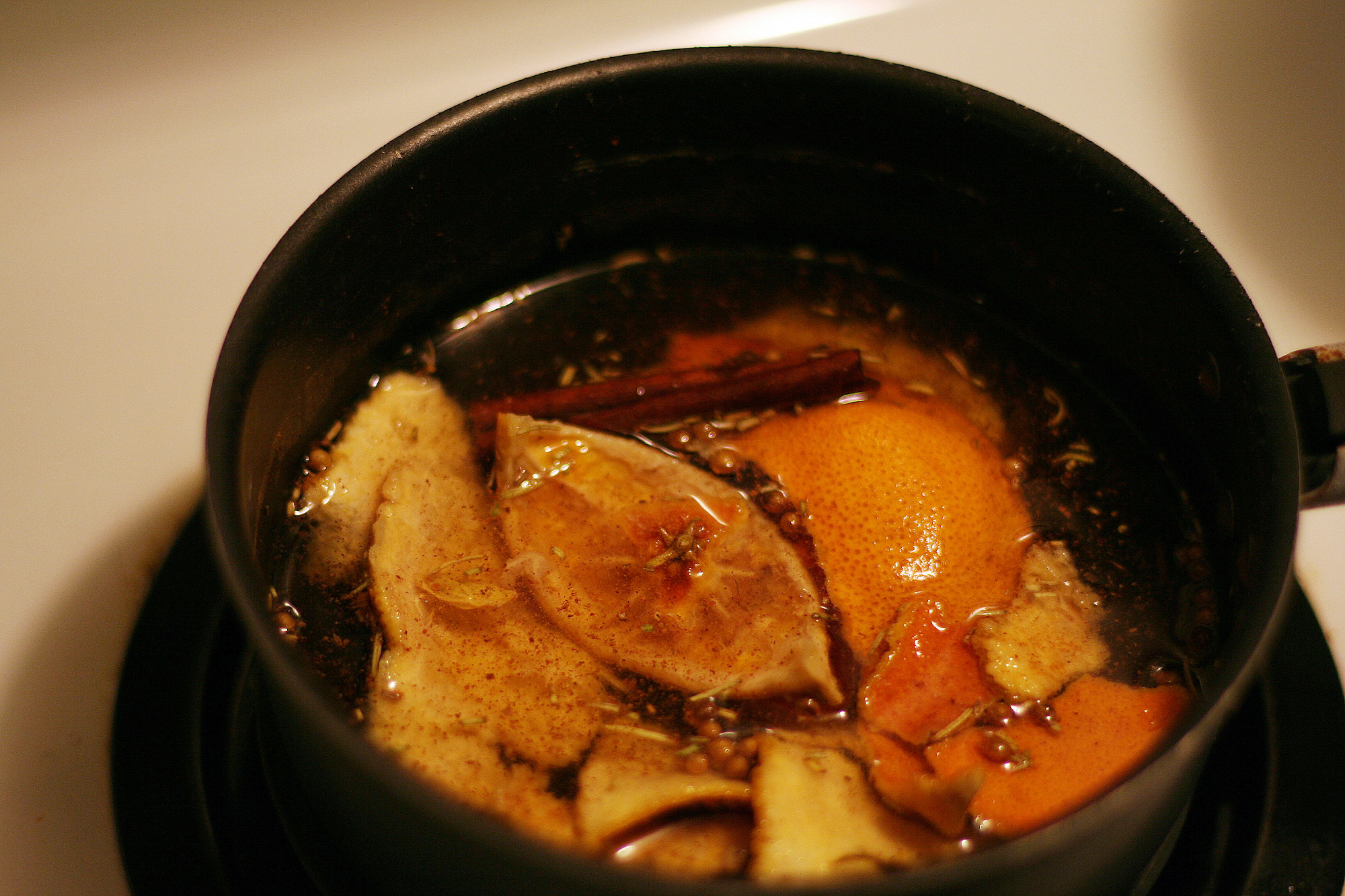 Fruit slices and cinnamon simmering in a pot on the stove