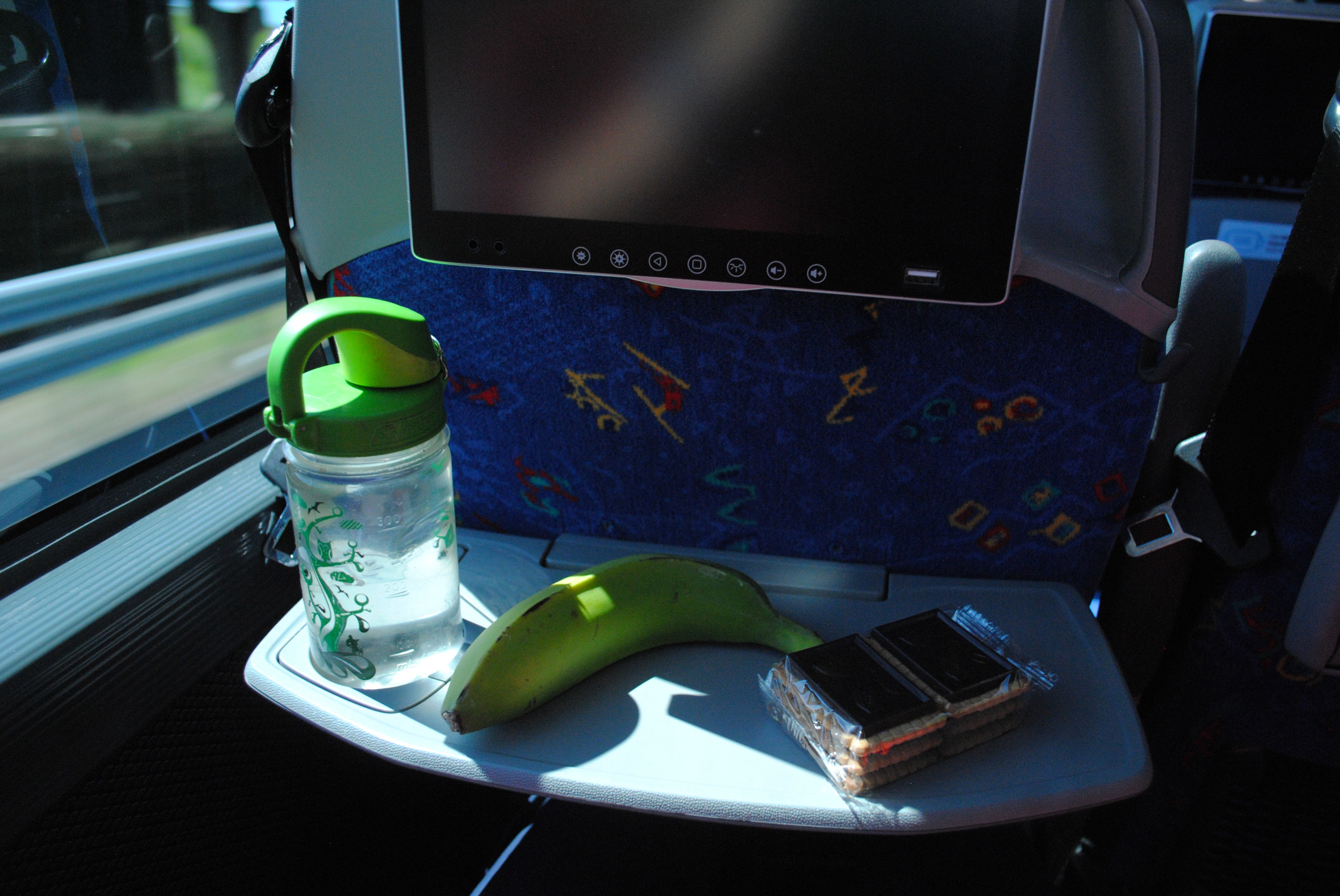 A tray table with a water bottle, banana, and cookies