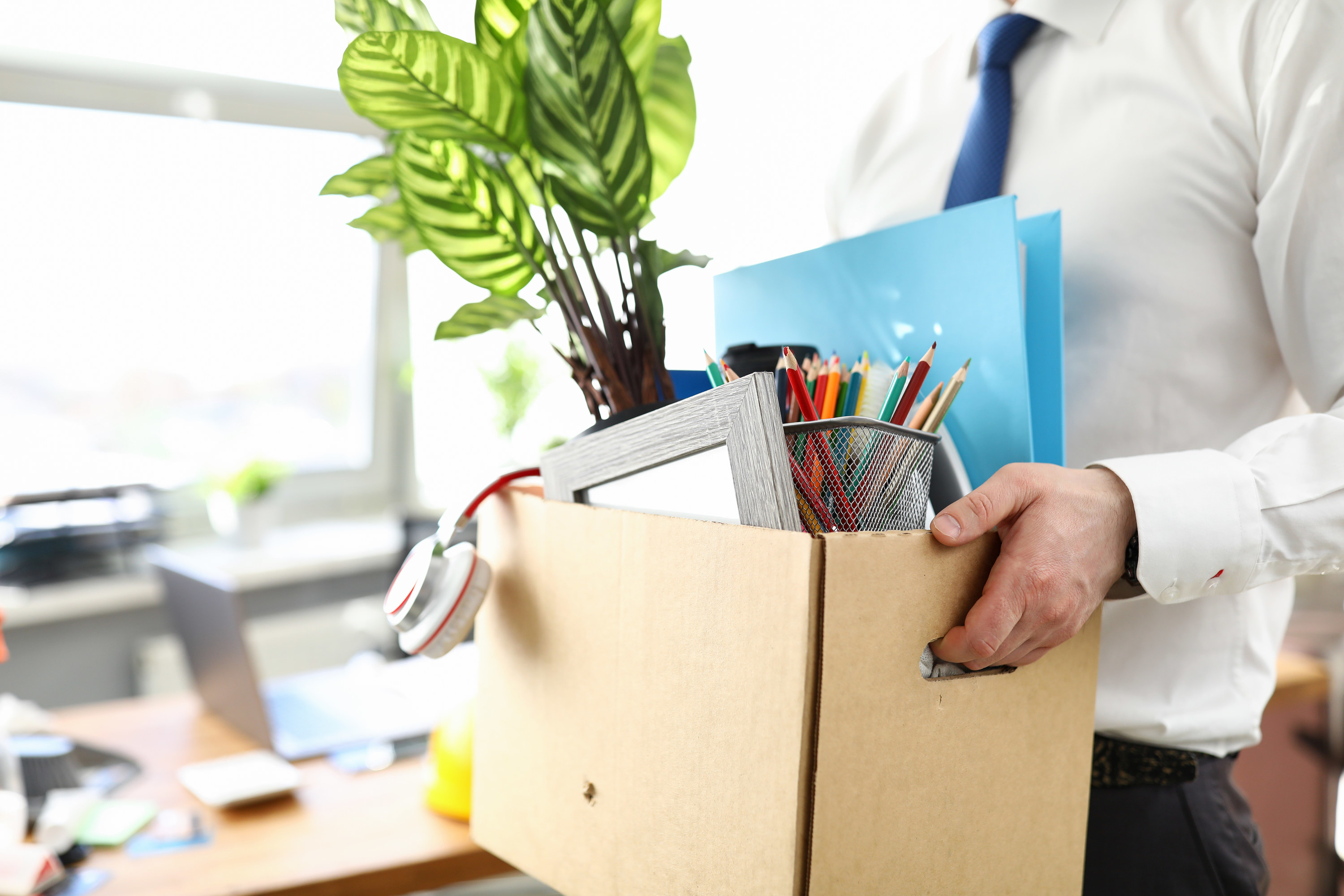 man carrying a box of his stuff out of an office