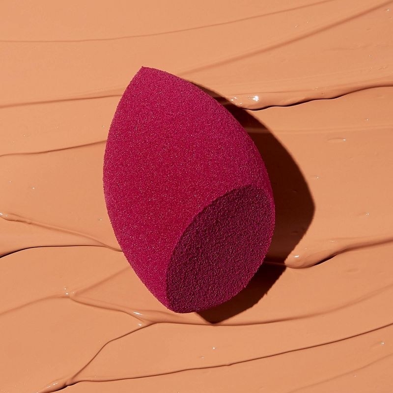 A red makeup sponge placed on top of liquid makeup