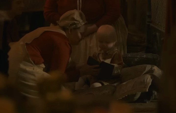 A nurse reads to baby Aegon