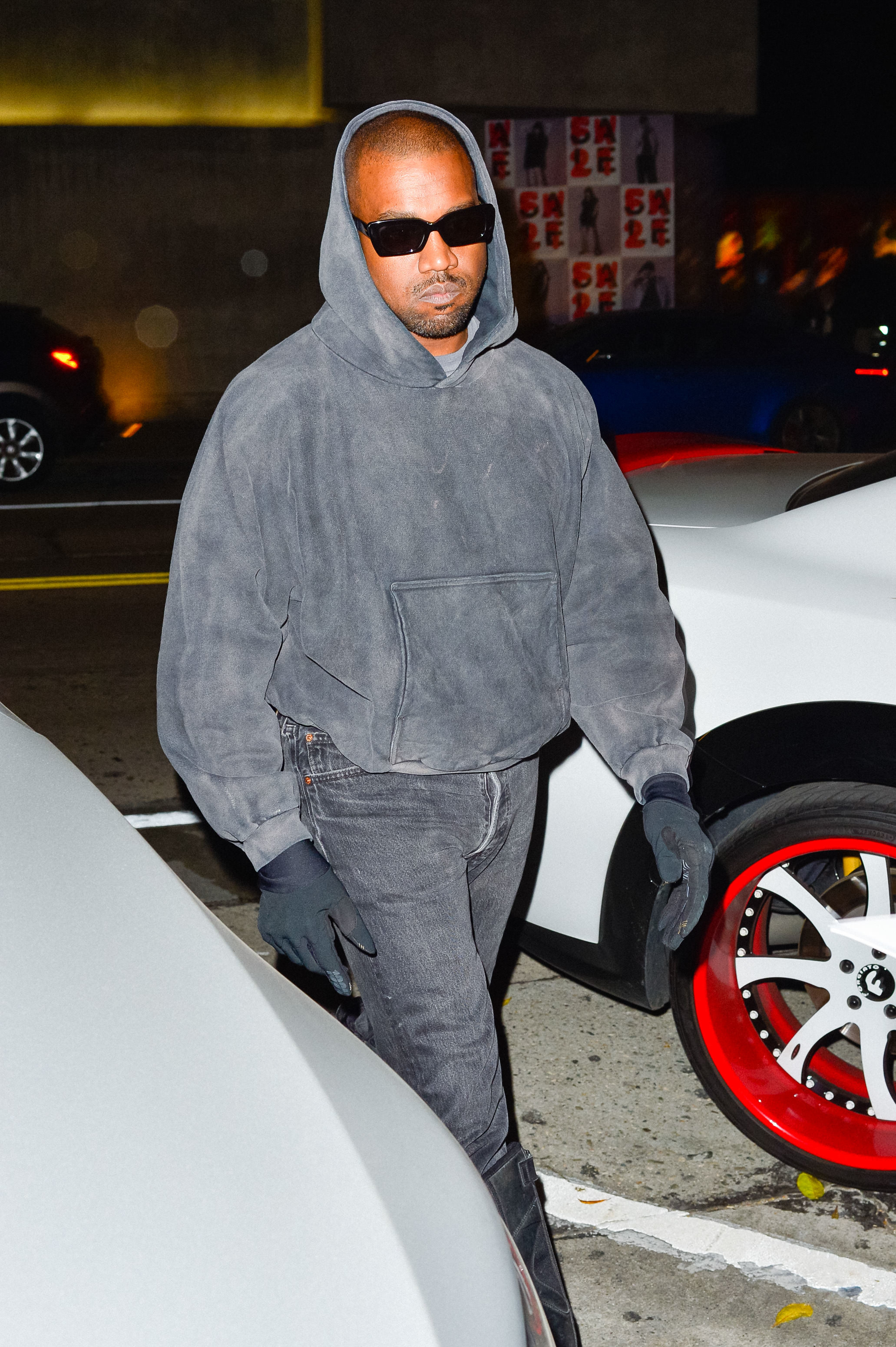 Ye wearing a hoodie and sunglasses