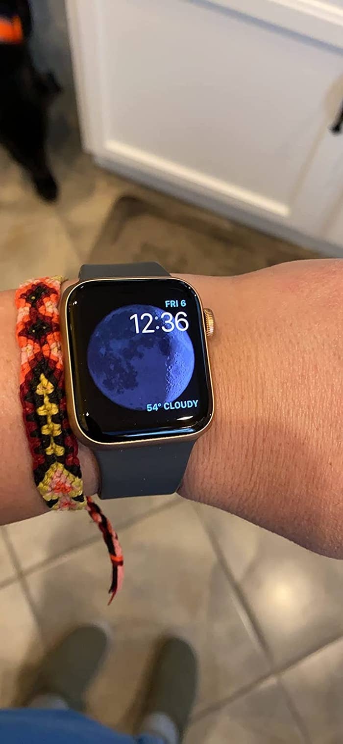 Reviewer with the watch on wrist showing a moon display face with the time, date, and weather