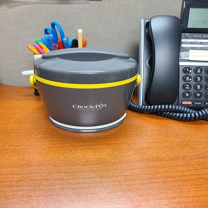 Another reviewer's photo of the grey crockpot sitting on their desk next to phone