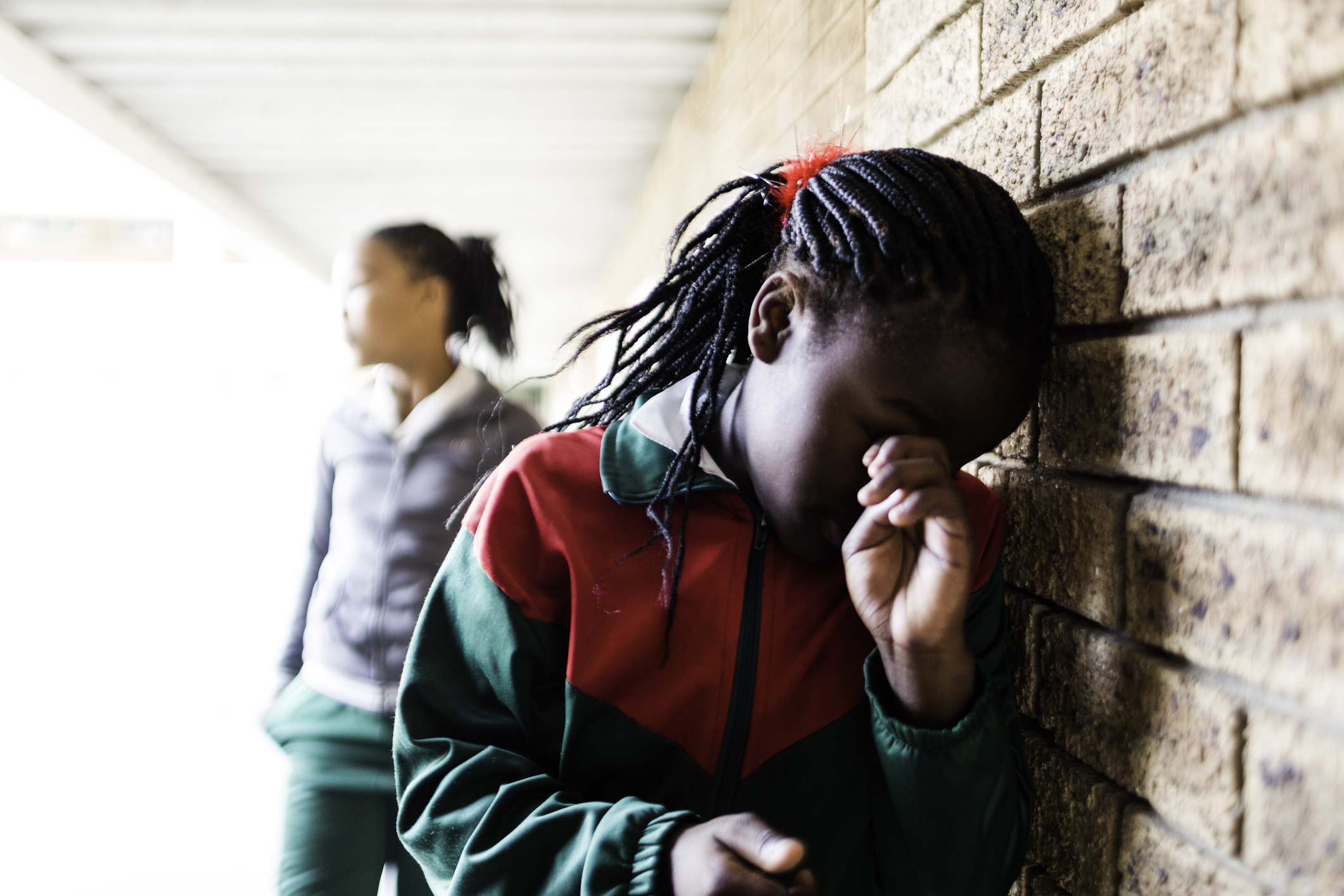 student crying and leaning against a wall