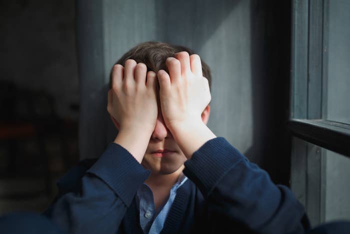 kid covering his face with his hands in despair