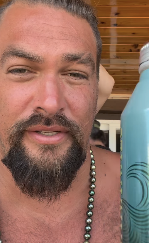 Jason Momoa talking and holding up an aluminum water bottle