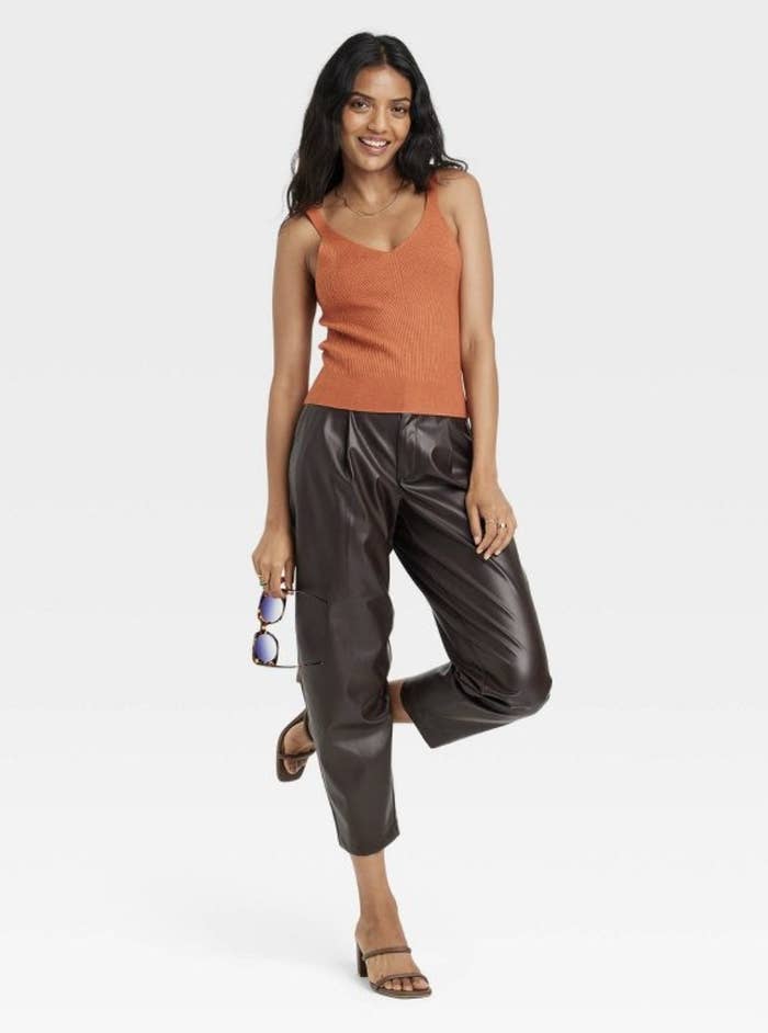 Model wearing the orange v-neck tank with black leather pants