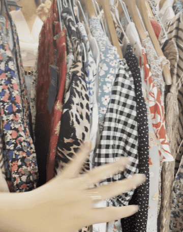 GIF image of a hand running through various printed dresses on a rail