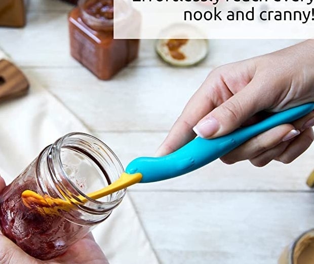 somebody using the spatula to get jam out of a jar