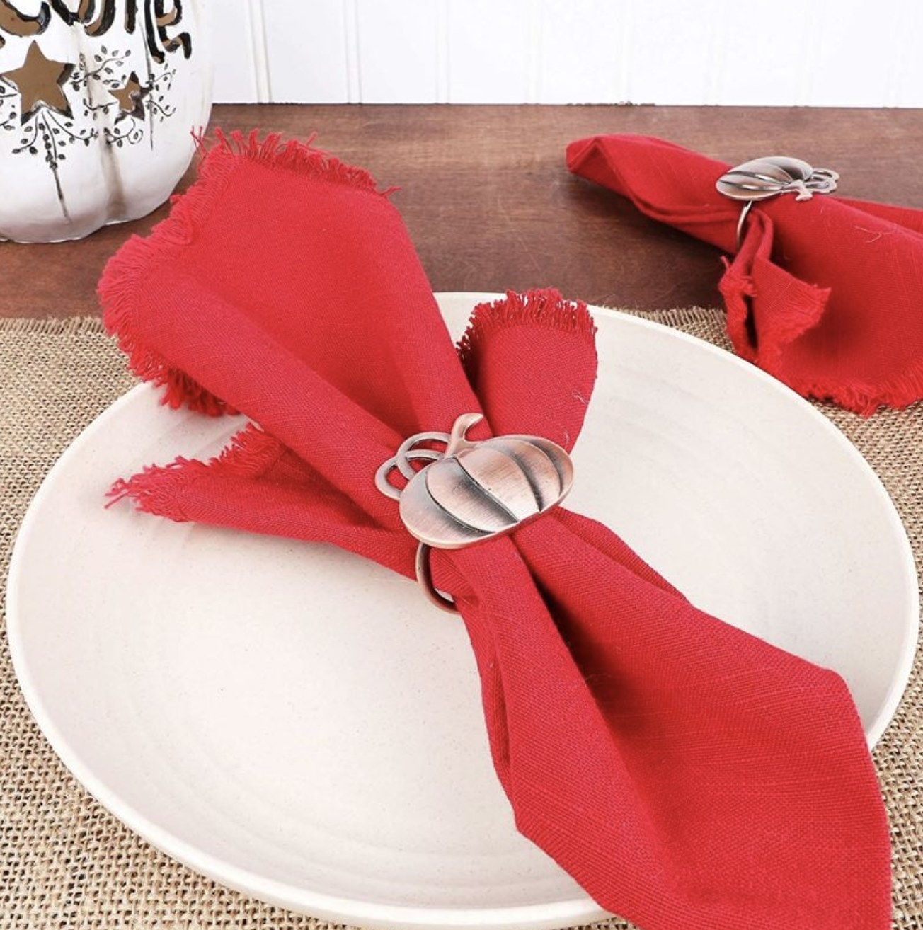 A plate with a red napkin displayed with the bronze pumpkin ring