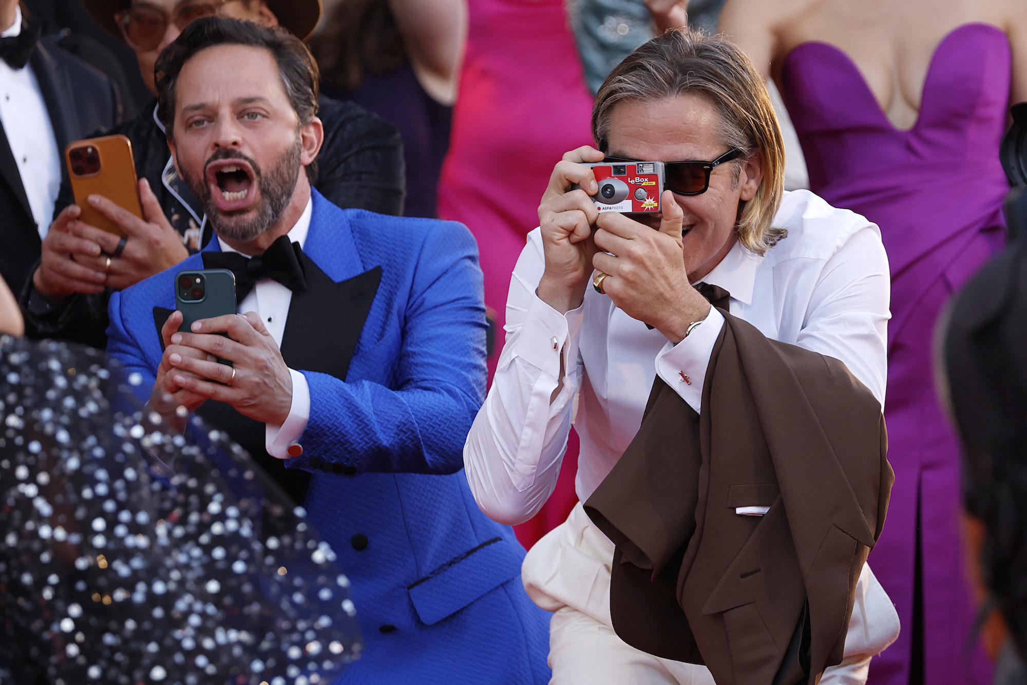 Chris holding up a disposable camera as he takes photos next to Nick Kroll
