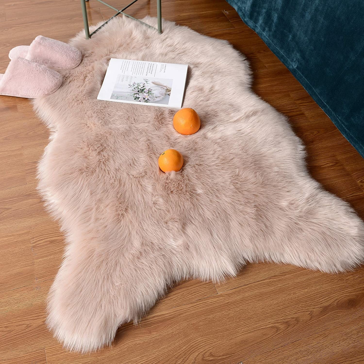 The rug on a wood floor with a magazine, slippers, and oranges on top of it