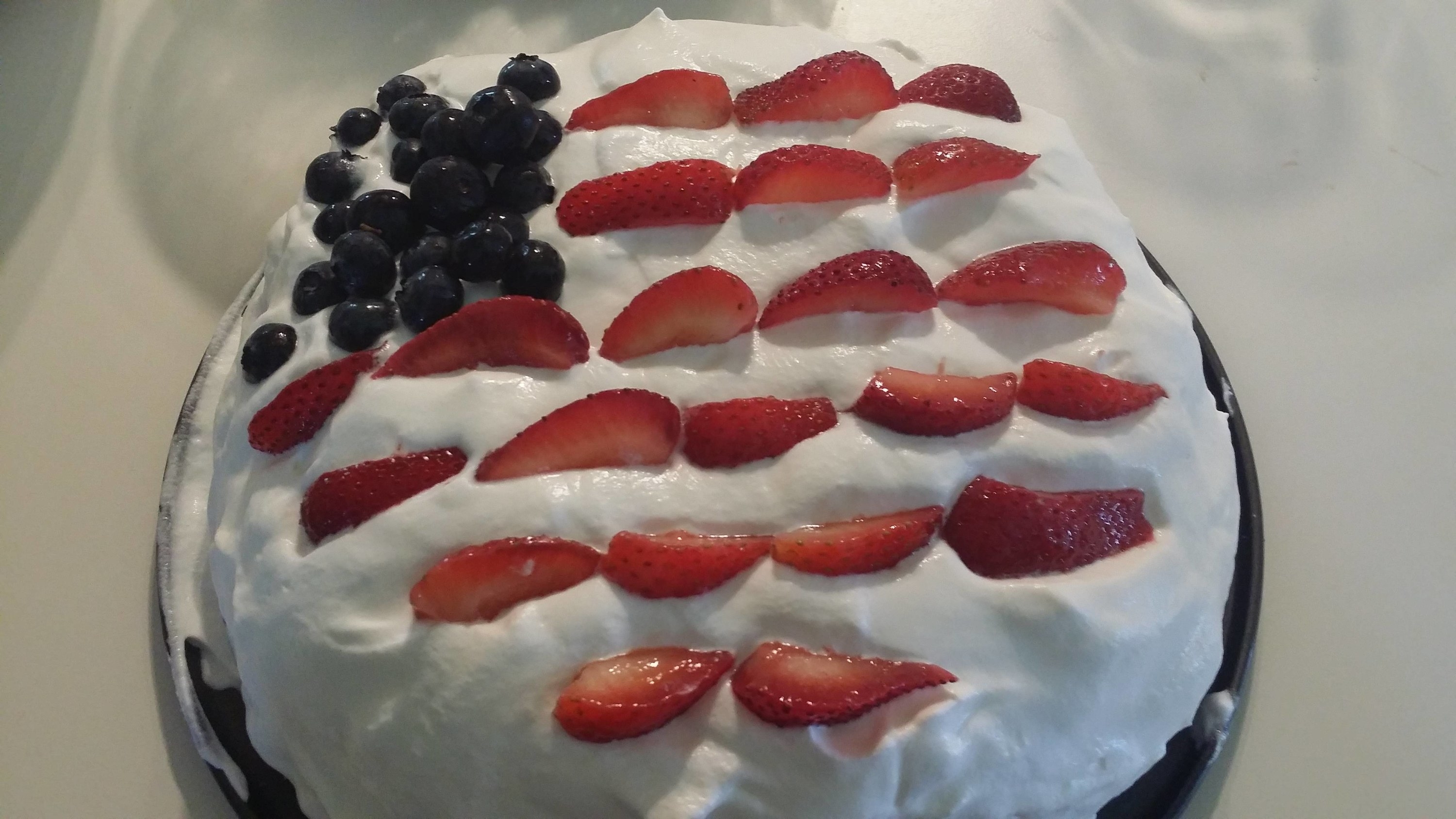 A pavlova covered in strawberries and blueberries decorated to look like the US flag