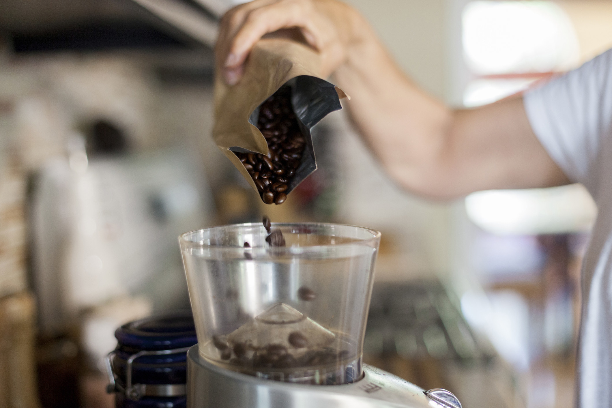 Someone pouring coffee grounds into a coffee maker