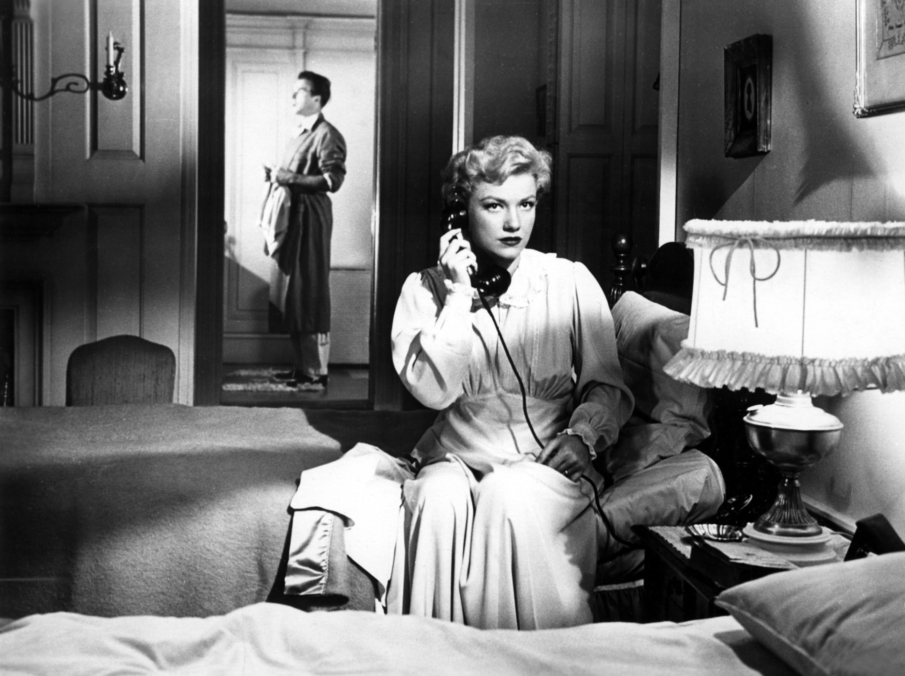 Roger Dann standing in the background while Anne Baxter is on the phone.