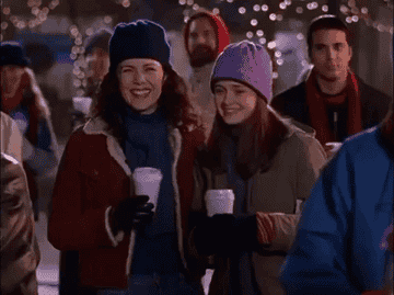a gif of lorelai gilmore and rory gilmore drinking coffee and laughing