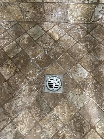 White flower shaped drain stopper lying over reviewer's shower drain