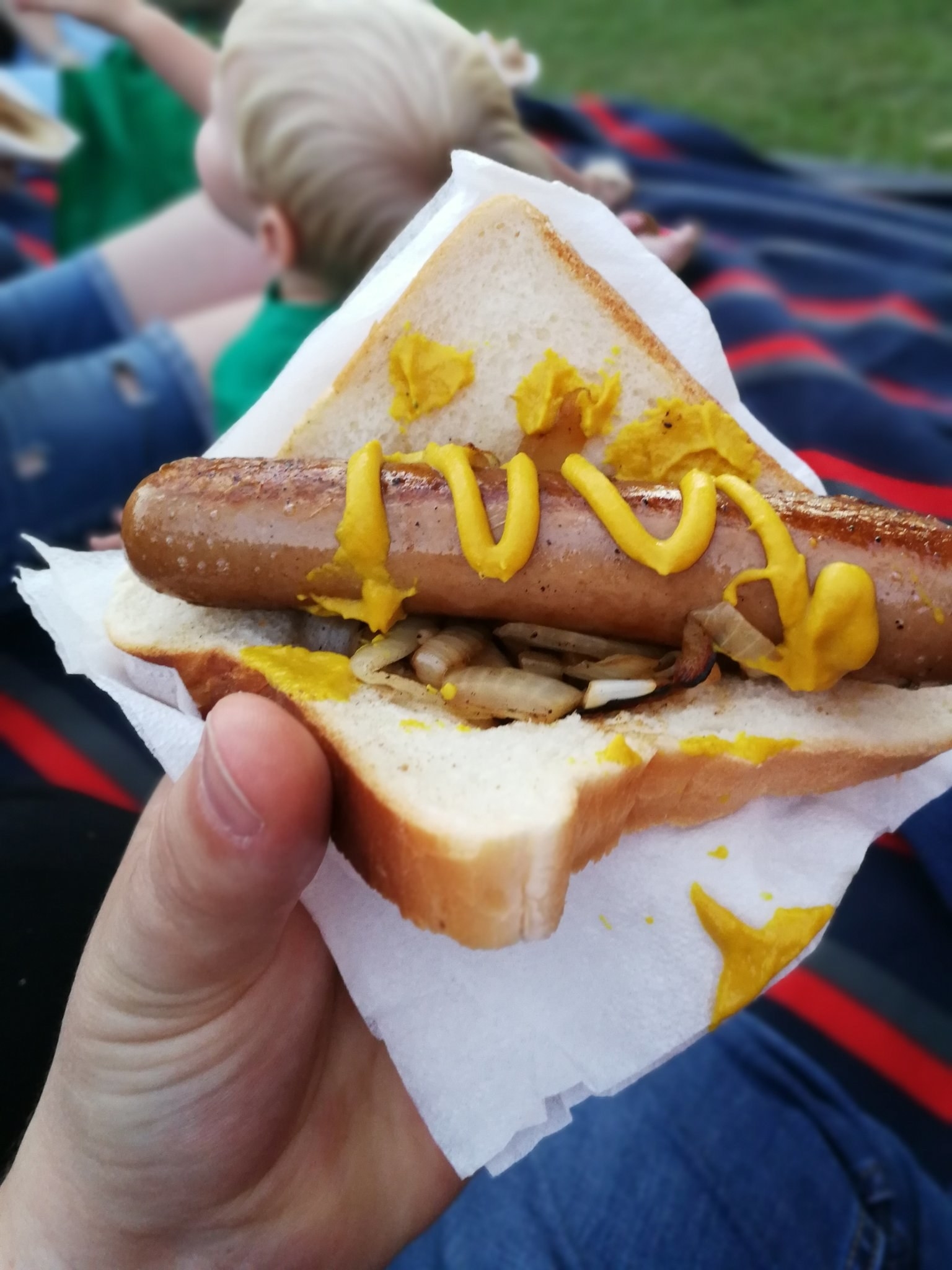 A sausage on top of onions in a piece of bread, topped with mustard