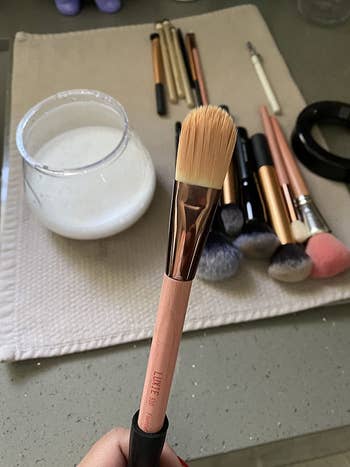 A reviewer's makeup brush with a tan tint on the bristles from makeup
