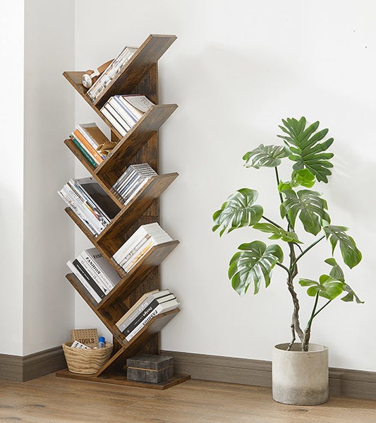 Several books on the book tree, a plant is next to it
