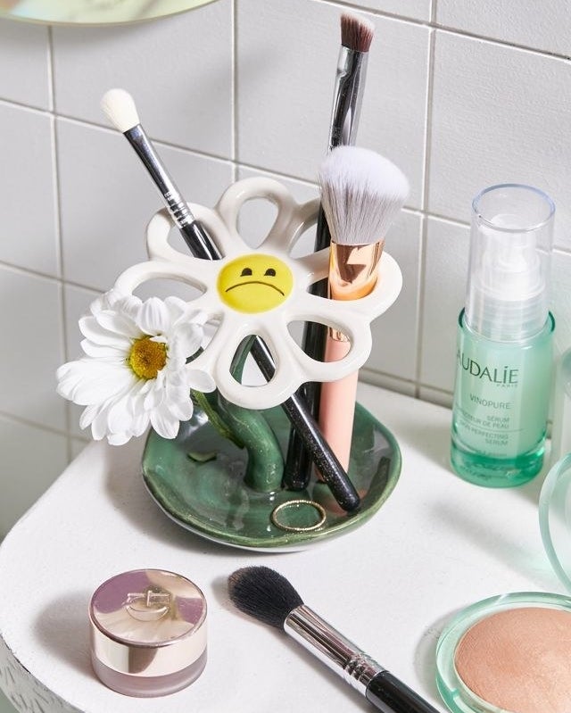 a daisy-shaped makeup brush holder on a bathroom counter