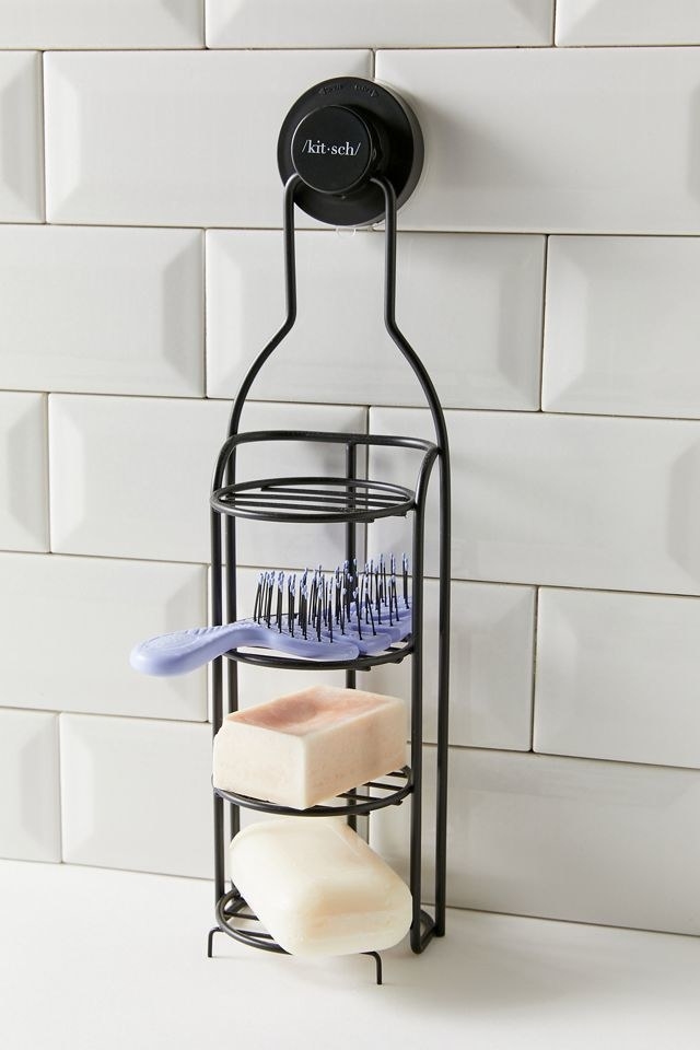a four-tier grated shower caddy with soaps and a hair brush on it
