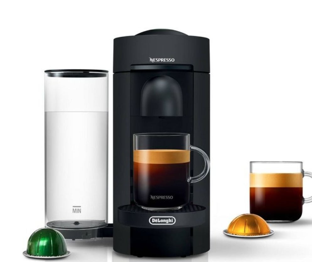 the black coffee maker with water reservoir, two cups of coffee and a gold and a green pod