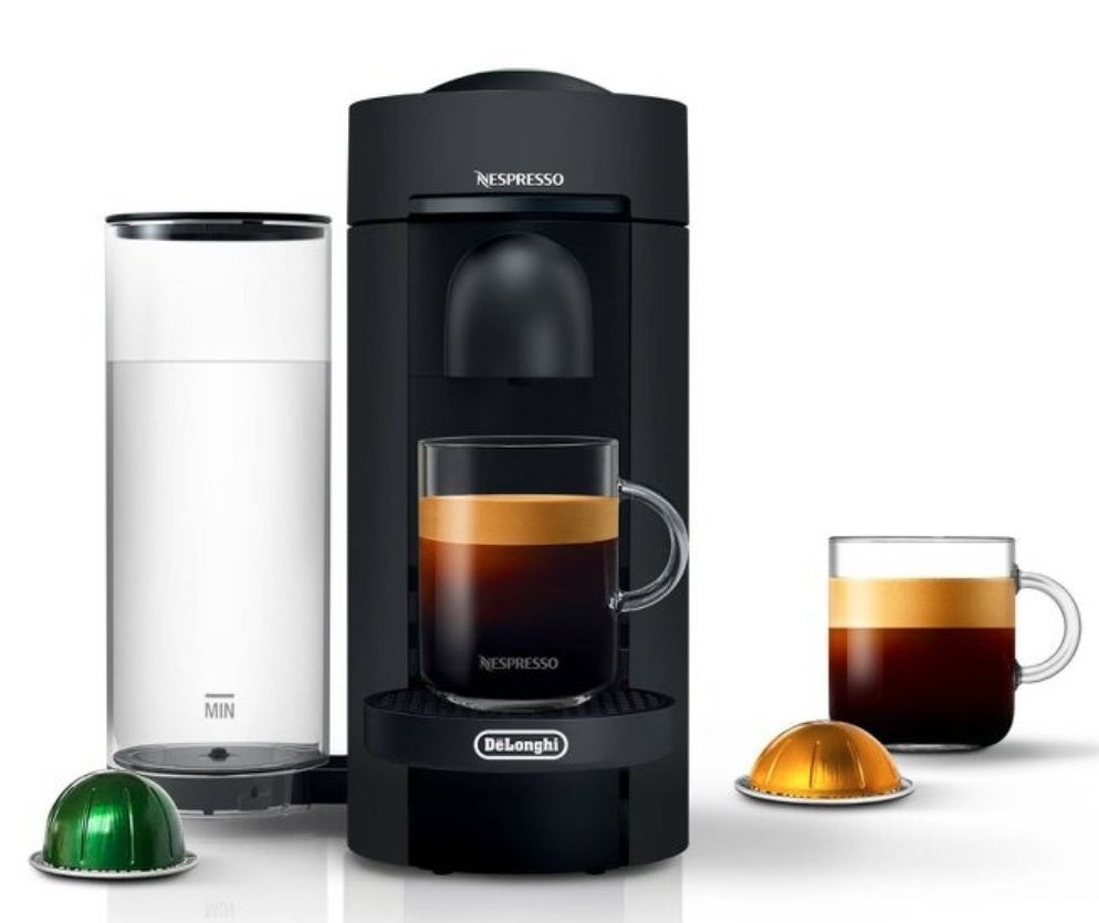 the black coffee maker with water reservoir, two cups of coffee and a gold and a green pod