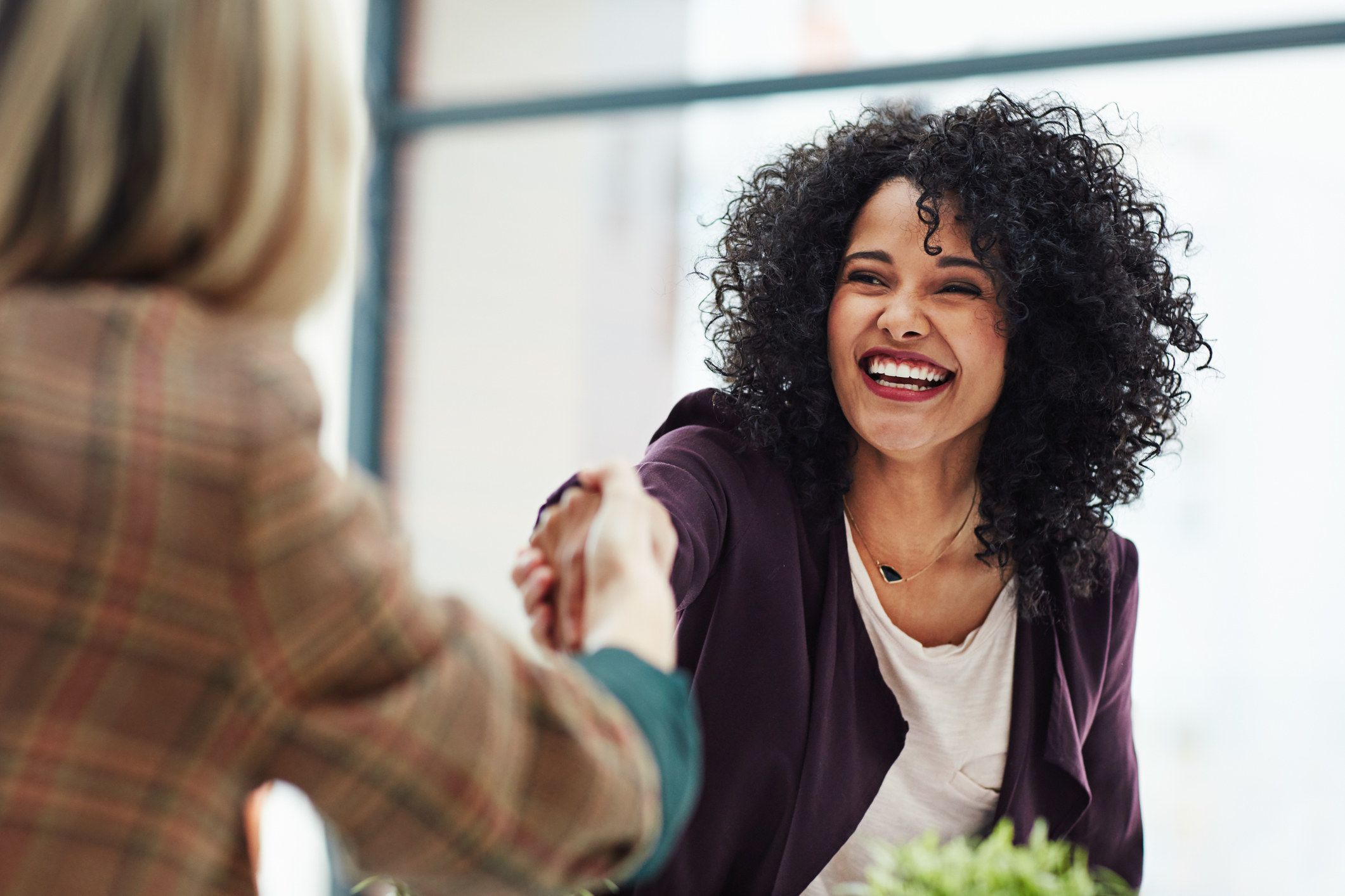 Woman smiling and shaking hands with another person