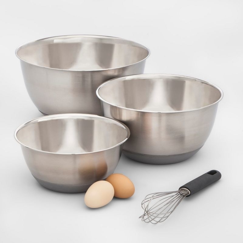 the three silver bowls with black plastic bottoms, next to two eggs and a whisk