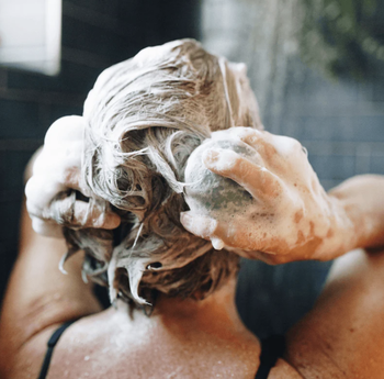 Model using a shampoo bar to wash their hair