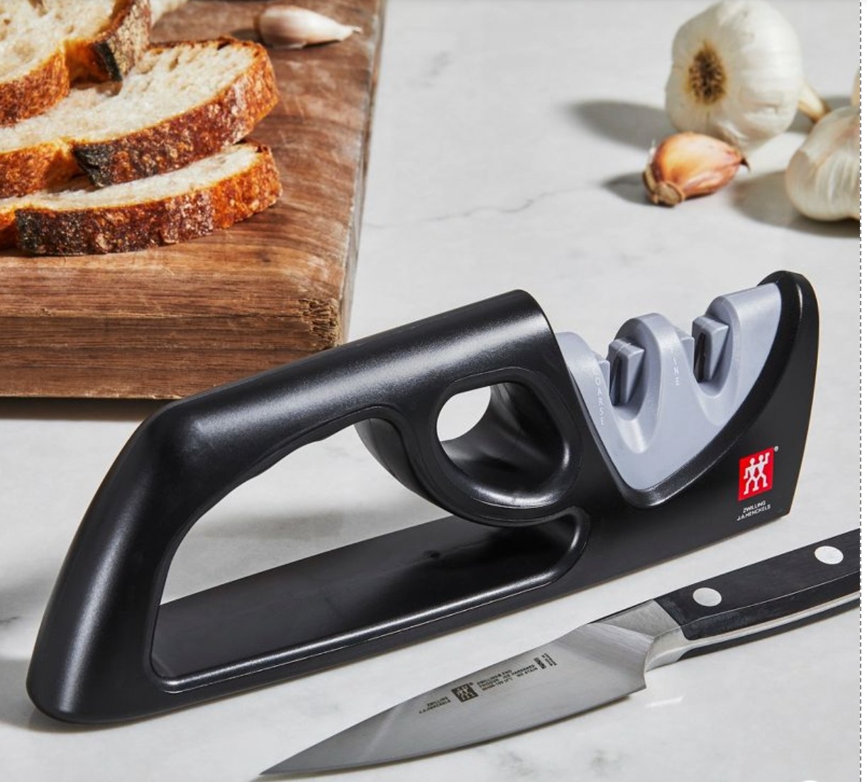 the black sharpener on a counter with bread, garlic, and a knife