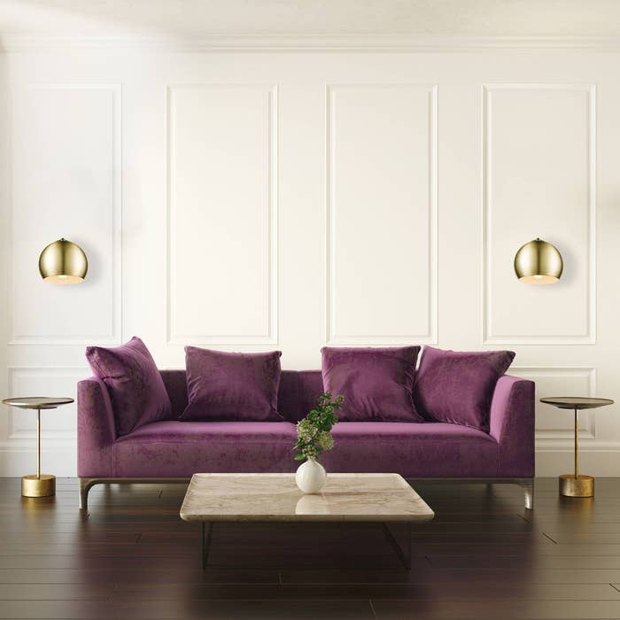 the globe sconces on two sides of a purple couch