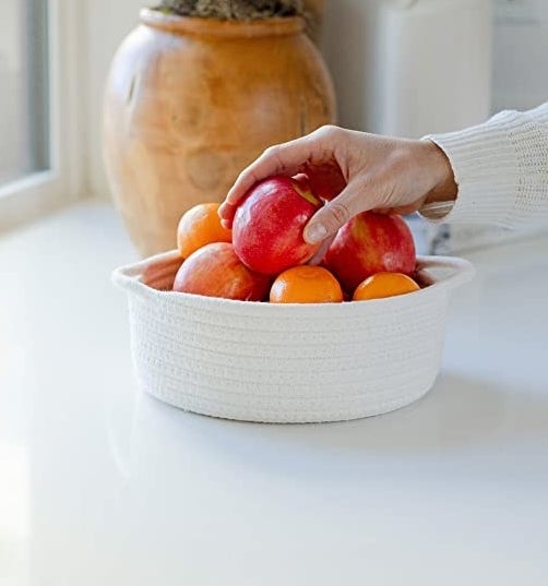 a person&#x27;s hand reaching for fruit from the woven basket
