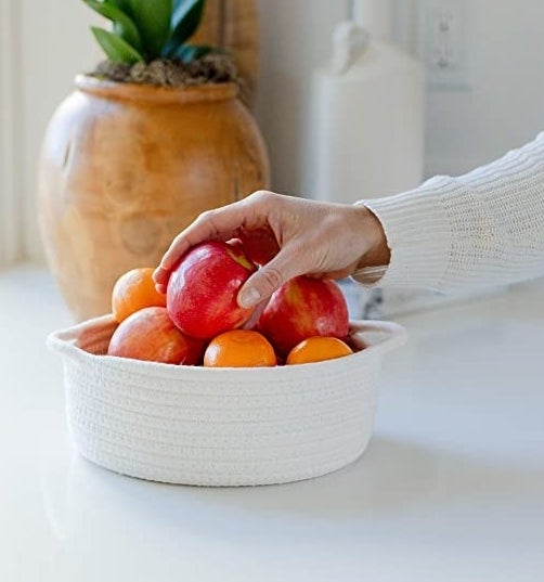 a person&#x27;s hand reaching for fruit from the woven basket