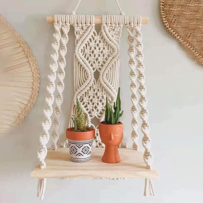 a macrame shelf hanging from the wall with plants on it